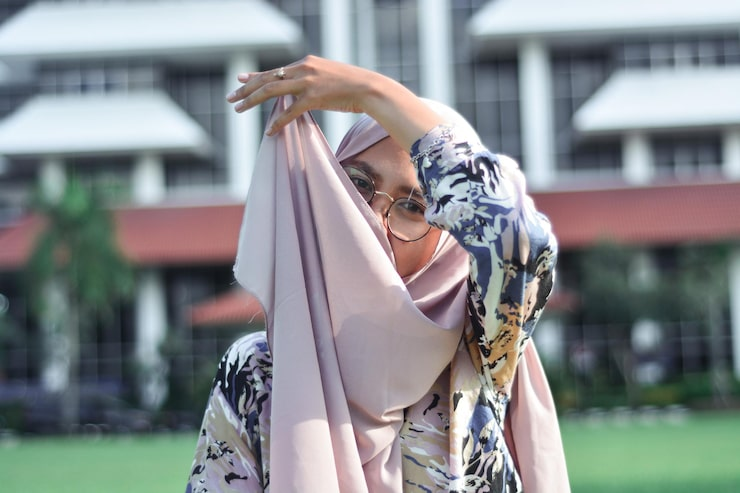 Woman Adjusting Hijab in Front of Building.png