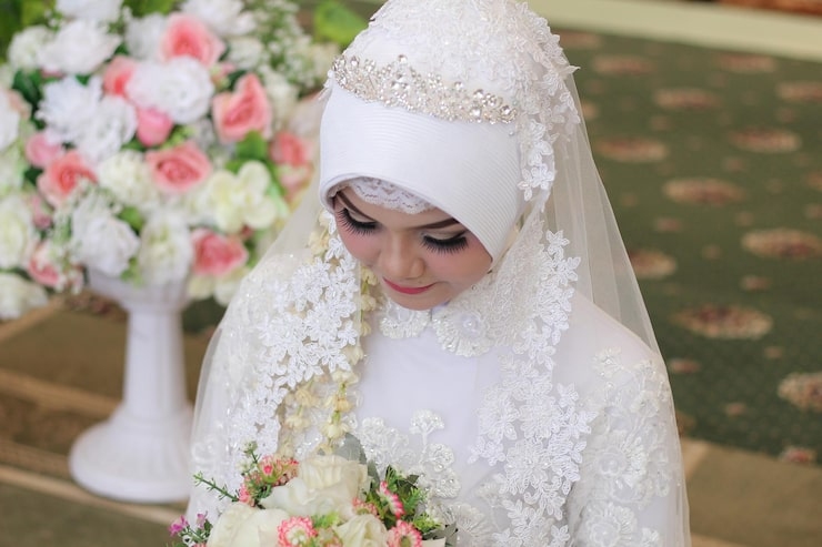 Muslim bride in white wedding attire with floral bouquet.jpg