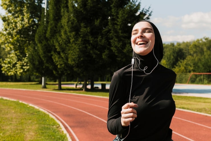Woman in hijab jogging on a track with earphones.jpg