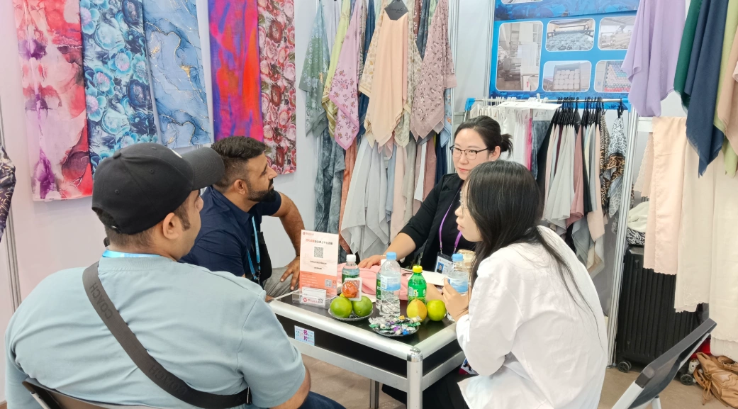 Jinlai Textile team discussing wholesale printed scarf customization with international clients at a trade show..webp